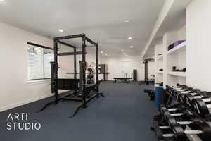 Living room configured as exercise room with an exterior entrance, kitchenette, textured ceiling, and recessed lighting
