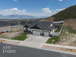 Ranch-style house featuring a garage, a mountain view, driveway, a residential view, and stone siding