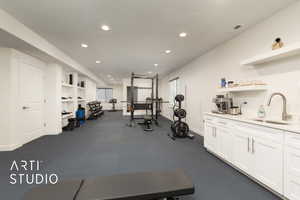 Living room configured as exercise room with an exterior entrance, kitchenette, textured ceiling, and recessed lighting