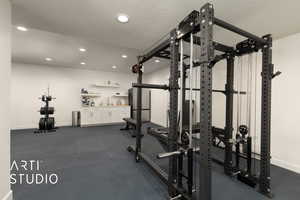 Living room configured as exercise room with an exterior entrance, kitchenette, textured ceiling, and recessed lighting