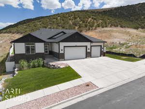 View of front of house featuring an attached garage, concrete driveway, a mountain view, and stone siding