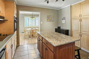 Kitchen featuring crown molding, a center island, light tile patterned floors, black electric stovetop, and oven