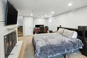 Bedroom with a desk, light carpet, recessed lighting, and a large fireplace