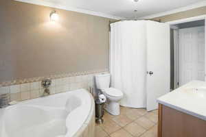 Full bath featuring a garden tub, ornamental molding, vanity, tile patterned floors, and a wainscoted wall