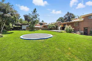 View of yard with a trampoline and a patio