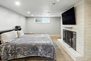 Bedroom with light colored carpet, recessed lighting, and a fireplace