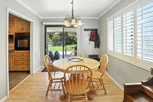 Dining area with ornamental molding, light wood-style floors, and a chandelier