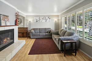 Living area featuring crown molding, wood finished floors, and a brick fireplace