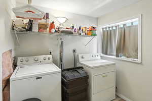 Washroom featuring washing machine and clothes dryer and baseboards
