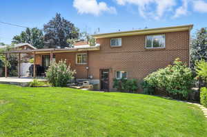 Rear view of property with brick siding, a yard, and a patio area