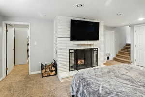 Carpeted bedroom with recessed lighting and a fireplace