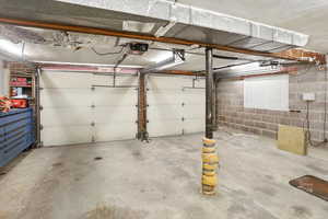 Garage featuring concrete block wall and a garage door opener