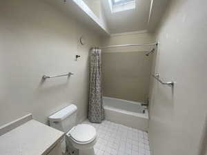 Full bathroom with a skylight, shower / bath combo with shower curtain, vanity, and tile patterned flooring