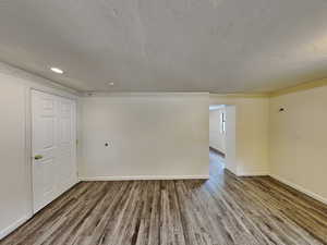 Unfurnished room featuring wood finished floors, a textured ceiling, and recessed lighting