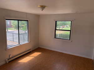 Unfurnished room with baseboard heating, healthy amount of natural light, and light wood-style floors