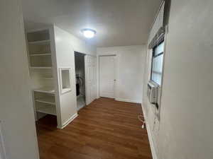 Corridor with wood finished floors and a textured ceiling