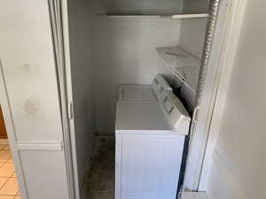 Washroom with washer and dryer and light tile patterned floors