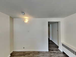 Spare room featuring radiator and dark wood-type flooring
