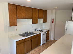 Kitchen with white appliances, light countertops, brown cabinets, and light tile patterned flooring