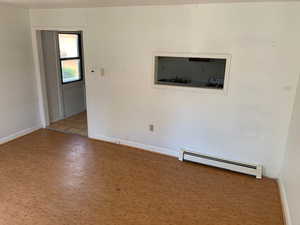 Empty room with a baseboard heating unit and wood finished floors