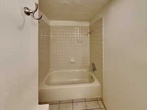 Full bath featuring a textured ceiling, tile patterned floors, and bathing tub / shower combination