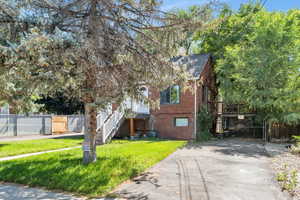 View of front of home featuring brick siding, concrete driveway, stairs, and a gate