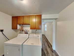 Laundry room featuring cabinet space, separate washer and dryer, and dark wood-type flooring