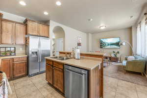 Kitchen featuring appliances with stainless steel finishes, arched walkways, open floor plan, light tile patterned floors, and recessed lighting
