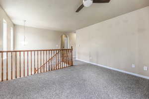 Unfurnished room featuring carpet, arched walkways, and ceiling fan