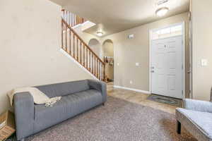 Foyer with arched walkways, stairway, tile patterned flooring, and carpet floors