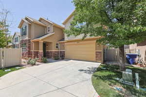 View of front facade featuring an attached garage, concrete driveway, stone siding, and stucco siding