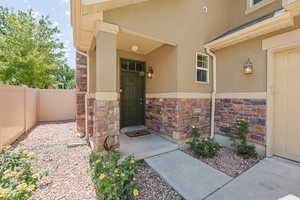 View of exterior entry with stone siding, stucco siding, and a garage
