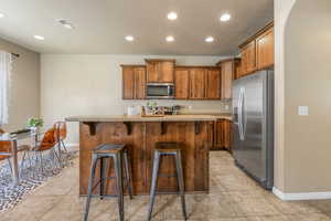 Kitchen with stainless steel appliances, recessed lighting, a kitchen bar, light countertops, and a kitchen island