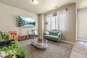 Tiled living room featuring baseboards and carpet