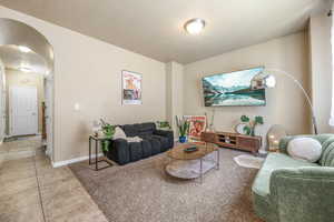 Living area featuring arched walkways and light tile patterned floors