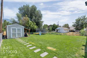 Fenced backyard featuring a trampoline and a storage shed