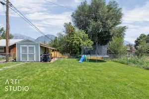 Fenced backyard with a trampoline, a storage unit, and a mountain view