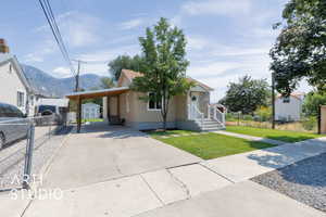 View of front of house featuring a storage unit, concrete driveway, a carport, and a mountain view