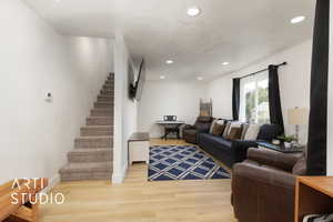 Living room with light wood-style floors, recessed lighting, stairway, and a textured ceiling
