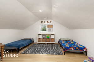 Bedroom featuring wood finished floors, a textured ceiling, and lofted ceiling
