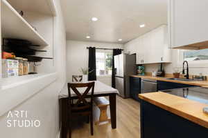 Kitchen featuring butcher block countertops, white cabinets, light wood-style flooring, recessed lighting, and appliances with stainless steel finishes