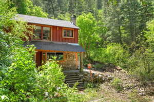 View of front of home featuring board and batten siding, a forest view, a shingled roof, and a chimney