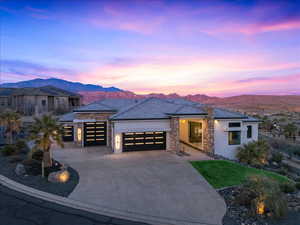 Prairie-style home with stone siding, a garage, stucco siding, and driveway