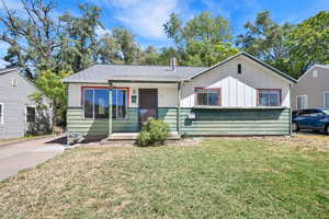 Bungalow-style home featuring a front lawn, roof with shingles, and board and batten siding