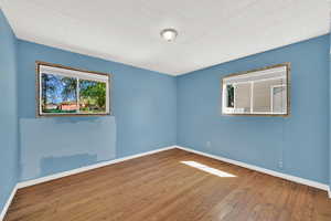 Empty room with healthy amount of natural light and wood finished floors