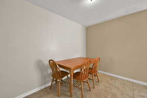 Dining area featuring light tile patterned flooring and a textured ceiling