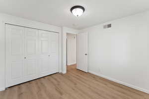 Unfurnished bedroom with light wood-style flooring and a closet