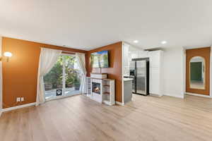 Unfurnished living room featuring light wood-style floors, recessed lighting, and a glass covered fireplace