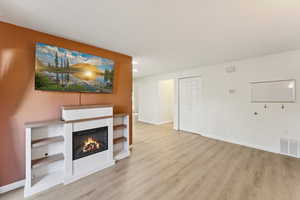 Unfurnished living room with a lit fireplace, light wood-style floors, and recessed lighting