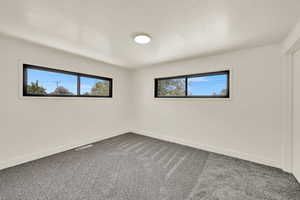 Spare room with dark carpet and a textured ceiling